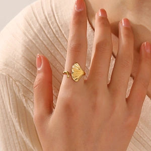 Elegant gold ginkgo leaf adjustable open ring shown on hand with a soft knit background
