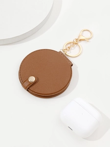 Detail of brown PU leather round mirror keychain pouch with gold clasp and headphones