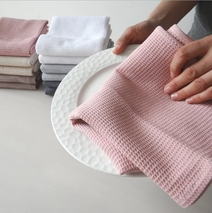 Detail showing various Morandi colored waffle weave cotton tea towels on a ceramic plate