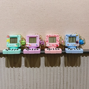 Dettaglio di portachiavi mini console di gioco retrò con campanelli e catene dorate