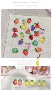Macro shot of 3D resin fruit nail art charms featuring translucent strawberry and pineapple