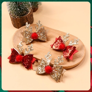 Close-up of glitter bow hair clips with reindeer antlers and pom poms on wooden tray