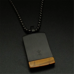 Macro shot of black square pendant featuring natural tiger eye stone and arrow engraving