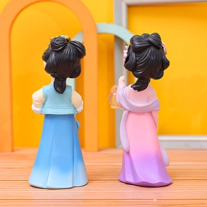 Detail of traditional Chinese style girl figurines in blue and pink on wooden surface