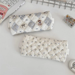 Close-up of quilted floral and bear pattern pencil cases with lace trim on a desk