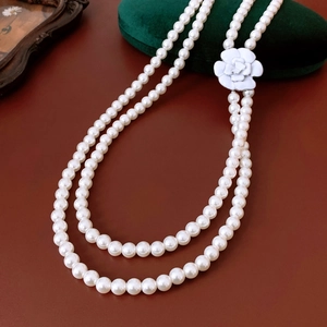 Close-up of double-layer glass pearl necklace with white camellia pendant on velvet