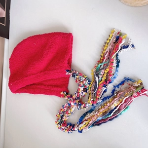 Detail of colorful long tassels and plush texture on pink ethnic winter beanie hat