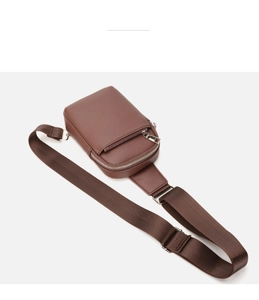 Detailed close-up of brown lychee grain leather sling bag with silver metal zippers
