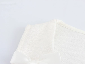 Détail de la texture en tweed blanc et du nœud en satin sur la robe sans manches