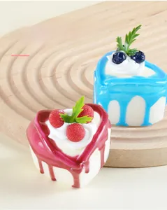 Detail view of heart-shaped mini cake models with cream and fruit on a wooden tray