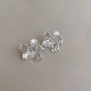 Close-up of silver metal flower earrings with textured irregular petals and glossy finish