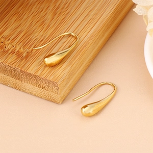 Elegant gold teardrop hook earrings made of minimalist stainless steel on wood background
