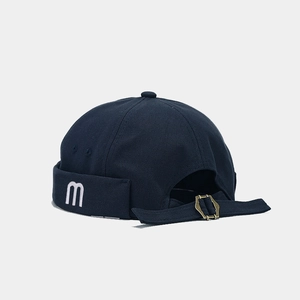 Detail of navy canvas docker hat featuring white M embroidery and metal back strap