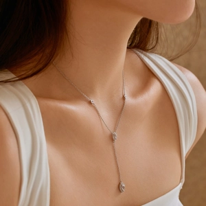 Macro detail of elegant Y-shaped silver necklace featuring sparkling teardrop crystals