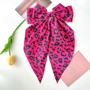 Pink leopard print bow hair clip with long ribbons on white marble surface