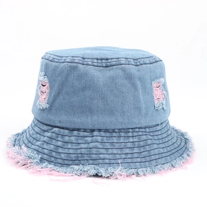 Dettaglio cappello a secchiello in denim blu con bordi sfrangiati rosa e strappi