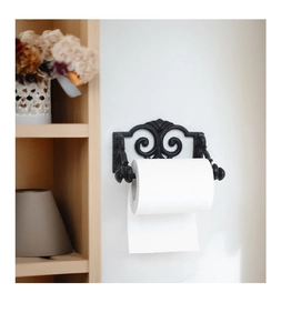 Close-up of black cast iron toilet paper holder with vintage scroll patterns on wall