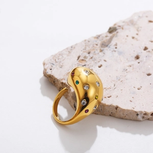 Detailed shot of gold plated titanium ring with colorful zircon stones on a textured stone