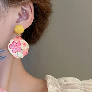 Detail of artistic oil painting sunflower earring featuring pink floral pattern and gold stud