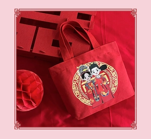 Close-up of a festive red canvas wedding gift bag with traditional cartoon couple print