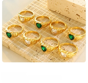 Detail view of heart-shaped green and clear gemstones set in vintage gold-plated rings