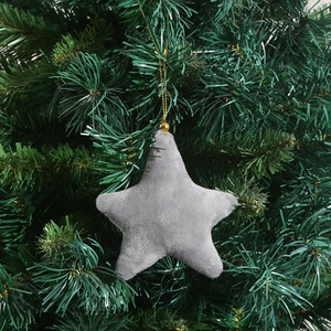 Close-up of a grey velvet star ornament hanging on green Christmas tree branches