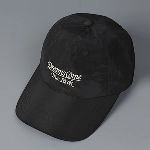Close-up of black nylon baseball cap with white 'Dreams Come True' embroidery detail
