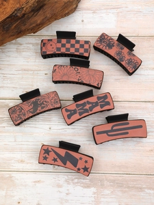 Flat lay of seven rectangular faux leather hair claws with various Western cowboy patterns
