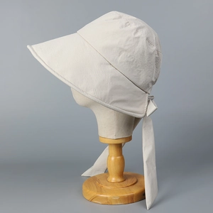 Detail of cream sun hat with large brim and ribbon bow on a vintage stand