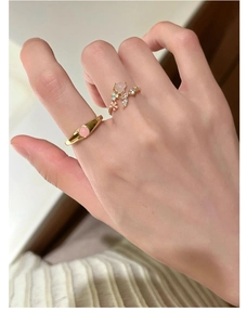 Close-up of gold s925 silver rings with pink gemstone flower and butterfly designs