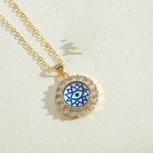 Close-up of golden necklace featuring a blue evil eye pendant with crystal zircon stones