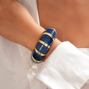 Detail of chunky blue acrylic bracelet with gold rings and glitter texture on model