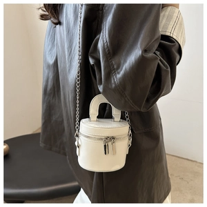 Mini sac cylindrique blanc avec chaîne argentée porté avec une veste en cuir marron
