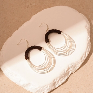Detail view of multi-layer silver metal hoops with dark brown fabric thread wrap
