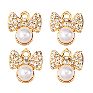 Detail of four golden bow pendants with inset pearls and sparkling cubic zirconia stones