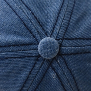 Macro shot of blue washed denim baseball cap top with button detail and stitching