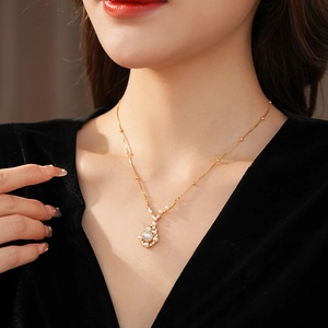 Close-up of a gold pearl pendant necklace with zircon crystals on a model's neck
