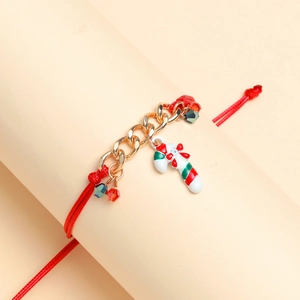 Detail of red braided rope bracelet with gold chain and festive candy cane pendant