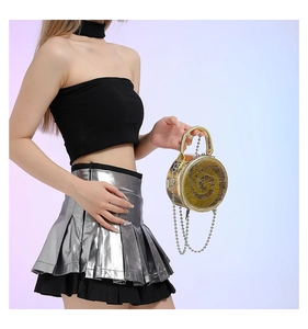 Detailed shot of a round gold handbag featuring unique texture and a silver chain strap