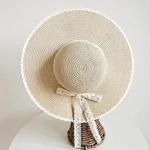 Cappello di paglia con bordo in pizzo bianco e nastro a fiocco su sfondo bianco