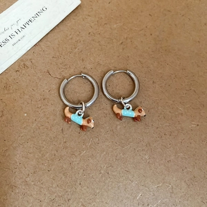 Close-up of cute enamel dachshund charms wearing blue polka dot sweaters on silver hoops