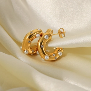 Detailed macro view of 18K gold-plated C-shaped earrings with pearls and zircons