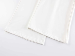 Detailed close-up of white wide-leg trousers hem showing fine fabric and flat stitching