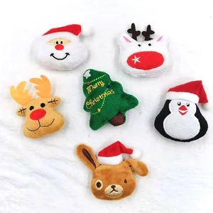 Flat lay of plush Christmas brooches featuring Santa, reindeer, penguin and tree motifs