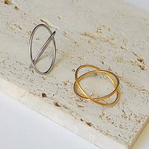 Close-up of interlocking silver and gold minimalist rings on a beige stone surface