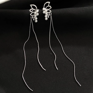 Close-up of silver butterfly earrings with white pearls and elegant long tassels