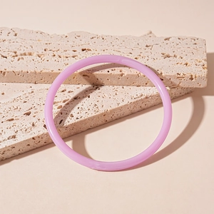 Gros plan du bracelet jonc en résine acrylique lavande sur des blocs de travertin naturel