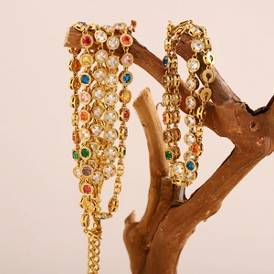 Detail of 18K gold plated necklace with colorful zircons hanging on a wooden branch