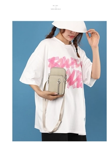 Detail view of beige crossbody phone bag with heart zipper and adjustable strap