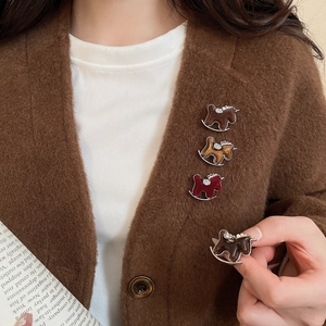 Detailed close-up of retro rocking horse brooches with rhinestones on a warm sweater